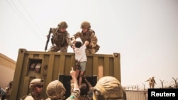 Soldații americani ajută un copil afgan în timpul evacuării de pe aeroportul din Kabul