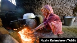 A girl lights a cooking fire in Tajikistan's Khatlon region.