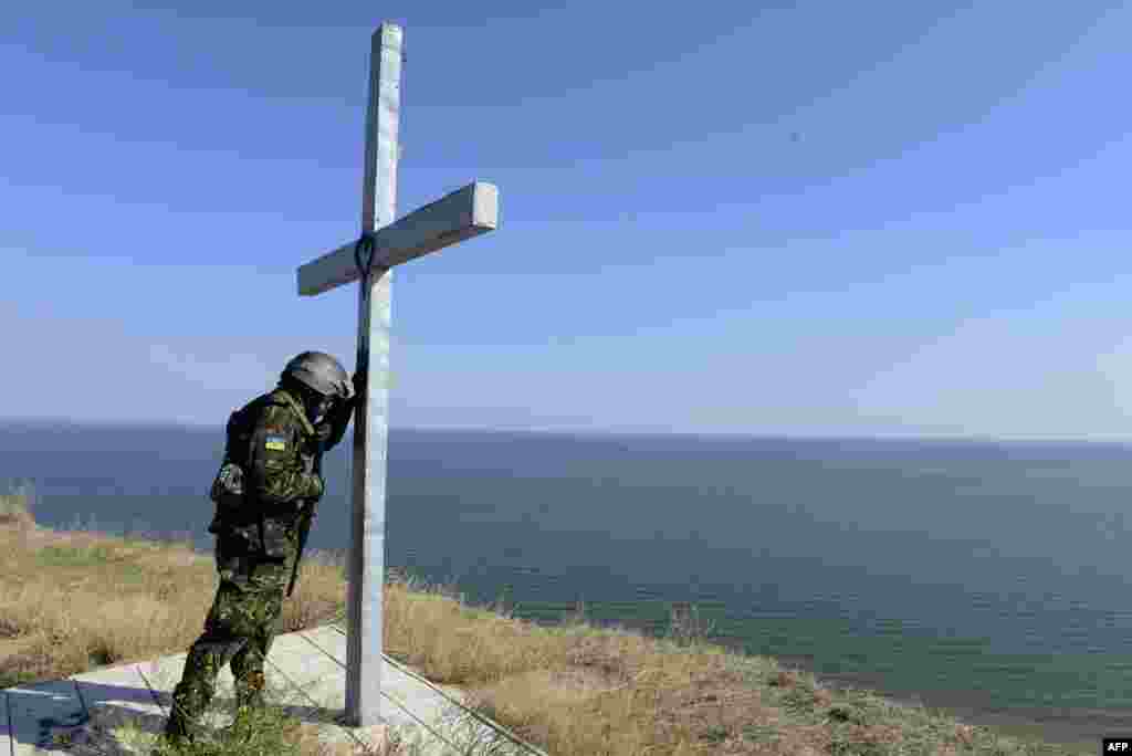 A soldier of the pro-Ukrainian St. Maria Battalion prays at a cross installed above the sea near the eastern city of Mariupol. (AFP/Alexander Khudoteply)