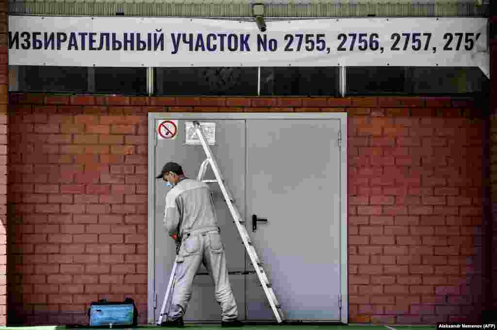 A worker fixes a banner at the entrance to a polling station in Moscow. (AFP/Alexander Nemenov)