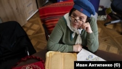 Диляра Бекирова пред старинния семеен Коран и пред кърпа, бродирана с кримскотатарския орнамент „орнек“.