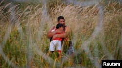 Біженець із дитиною на сербському боці угорсько-сербського кордону, 15 вересня 2015 року