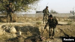 An Afghan soldier pulls belongings from an insurgent, dressed in army uniform, after an attack at the Jalalabad airport.