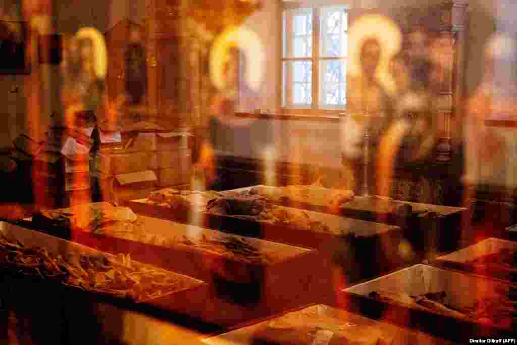 Coffins containing the remains of Russian and French soldiers who died during Napoleon&#39;s 1812 retreat are reflected in an Orthodox icon during a ceremony in a small church in the monastery of John the Precursor in the western Russian town of Viazma. The remains of 100 Russian and French soldiers, unearthed in Viazma, will be buried together on February 13. (AFP/Dimitar Dilkoff)