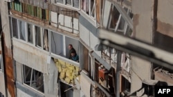 Residents look out of broken windows in a damaged residential building following a drone attack in Odesa on May 1.
