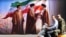 Men ride a scooter past a billboard featuring the images of the late founder of the Islamic Revolution supreme leader Ayatollah Ruhollah Khomeini (L), the Iran's slain supreme leader Ali Khamenei (C) and his son, the current supreme leader Mojtaba Khamene