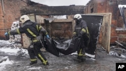 Firefighters carry the body of a local resident killed after a Russian drone hit his home in a residential neighborhood in Kharkiv on February 10.
