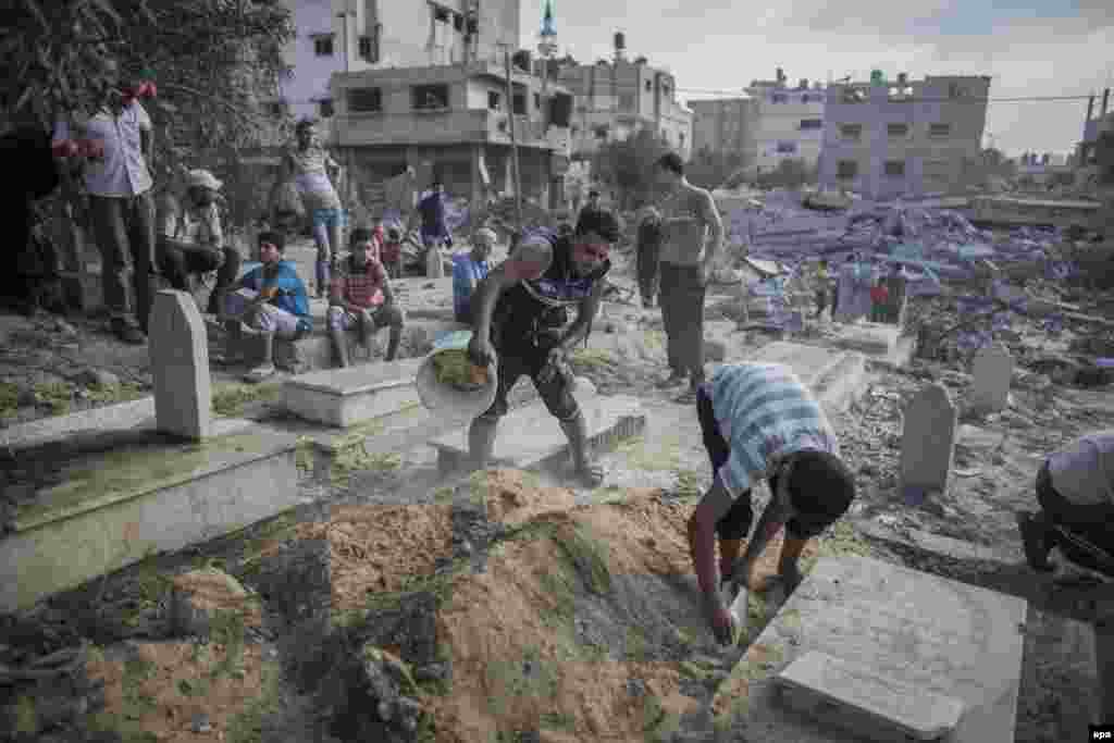 Palestinian men clean up graves from debris from a nearby house that was destroyed during an Israeli air strike during the Muslim holiday of Eid al-Fitr at the Sheikh Aduwan cementery in Gaza City, on July 28. (epa/Oliver Weiken)