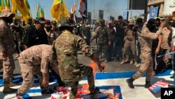 Iraqi Popular Mobilization Forces burn representations of U.S. and Israeli flags during "al-Quds" Day, Arabic for Jerusalem, in Baghdad, Iraq, Friday, May 31, 2019. Jerusalem Day began after the 1979 Islamic Revolution in Iran, when the Ayatollah Khomeini