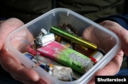 Мъж държи кутия с изхвърлени вейпове.