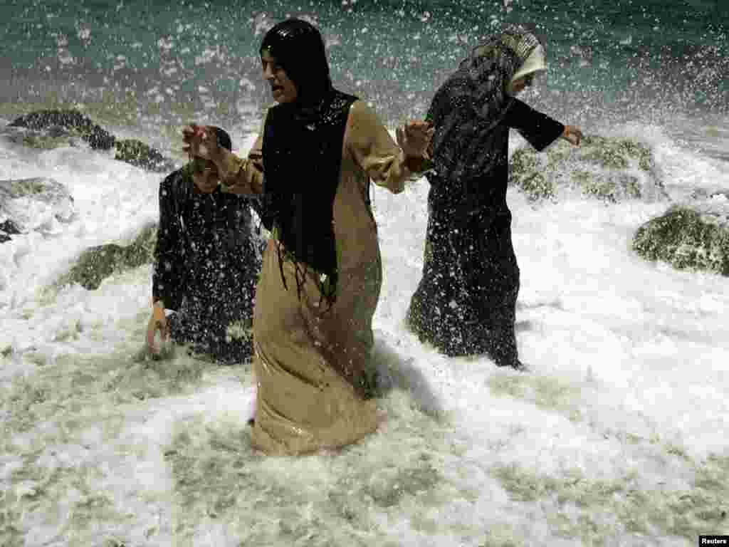 Three women cool off on the beach at Algiers, June 4, 2006. REUTERS/Zohra Bensemra 