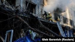 Firefighters work at the site of an apartment building and a supermarket hit by a Russian jet drone strike in Kyiv on September 26.