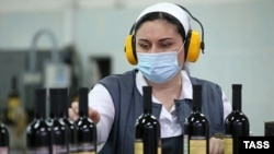 Оператор конвейера с упаковками для бутылок вина на винзаводе. Крым, 2020 год