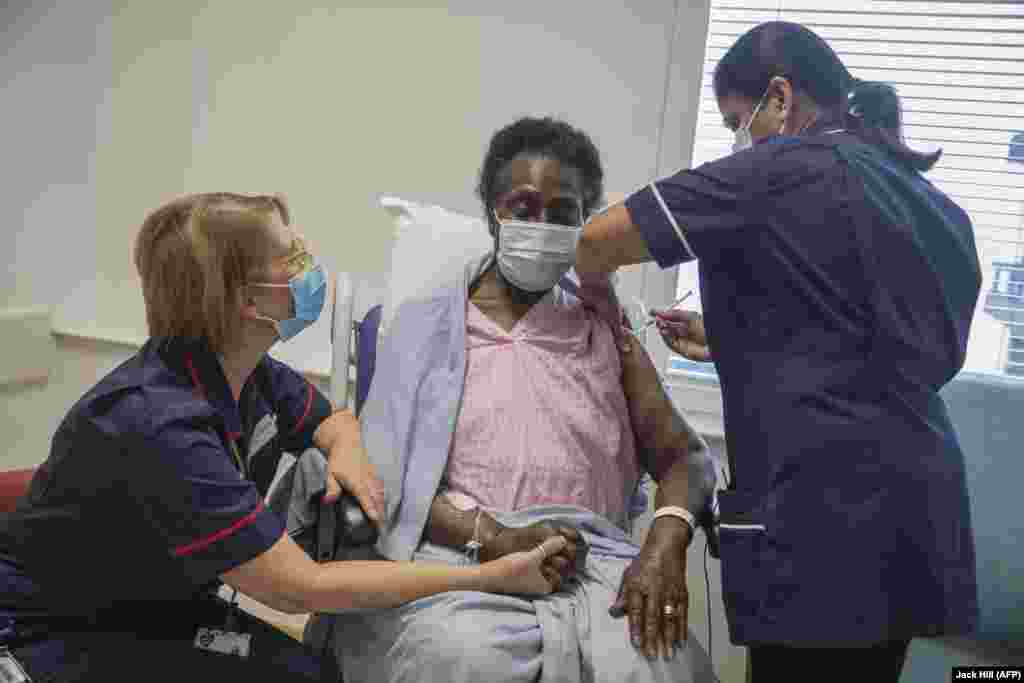 Старшая медсестра Дилхани Сомавира (справа) вводит вакцину Pfizer/BioNTech COVID-19 80-летней Джозефине Фали (в центре) в Королевской бесплатной больнице в Лондоне. Великобритания, 8 декабря 2020 года