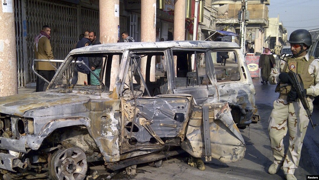 A soldier stands guard near a burnt vehicle after a bomb attack in Alawi district in central Baghdad on December 22.