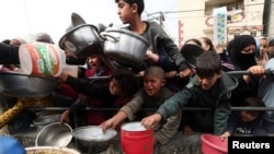 Fëmijët palestinezë duke pritur për të marrë ushqim nga nga agjencitë e bamirësisë në një kohë mungese ushqimi në kampet e mbipopulluara në Rafah, jug të Rripit të Gazës më 13 shkurt 2024, ku Izraeli synon të nisë një ofensivë.