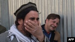 Two Afghan men weep for their relatives in front of the main gate of a military hospital in Kabul after a deadly six-hour attack claimed by the Islamic State group on March 8.