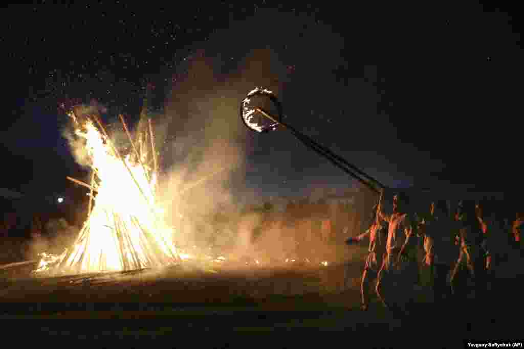 Villagers walk around a bonfire celebrating the summer solstice in Okunevo, some 200 kilometers northeast of Omsk in Siberia.