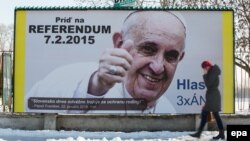 Женщина проходит мимо рекламного щита с портретом Папы Римского Франциска. Братислава, Словакия, 6 февраля 2015 года.