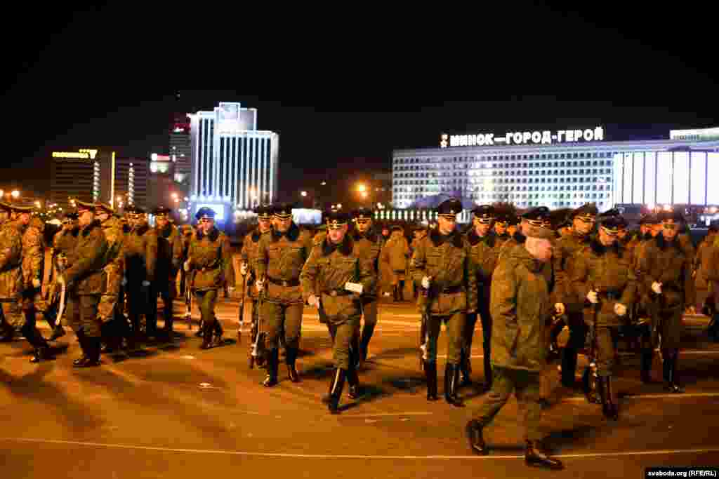 Soldiers walk across the square with a &quot;Minsk-Hero-City&quot; sign in the background.