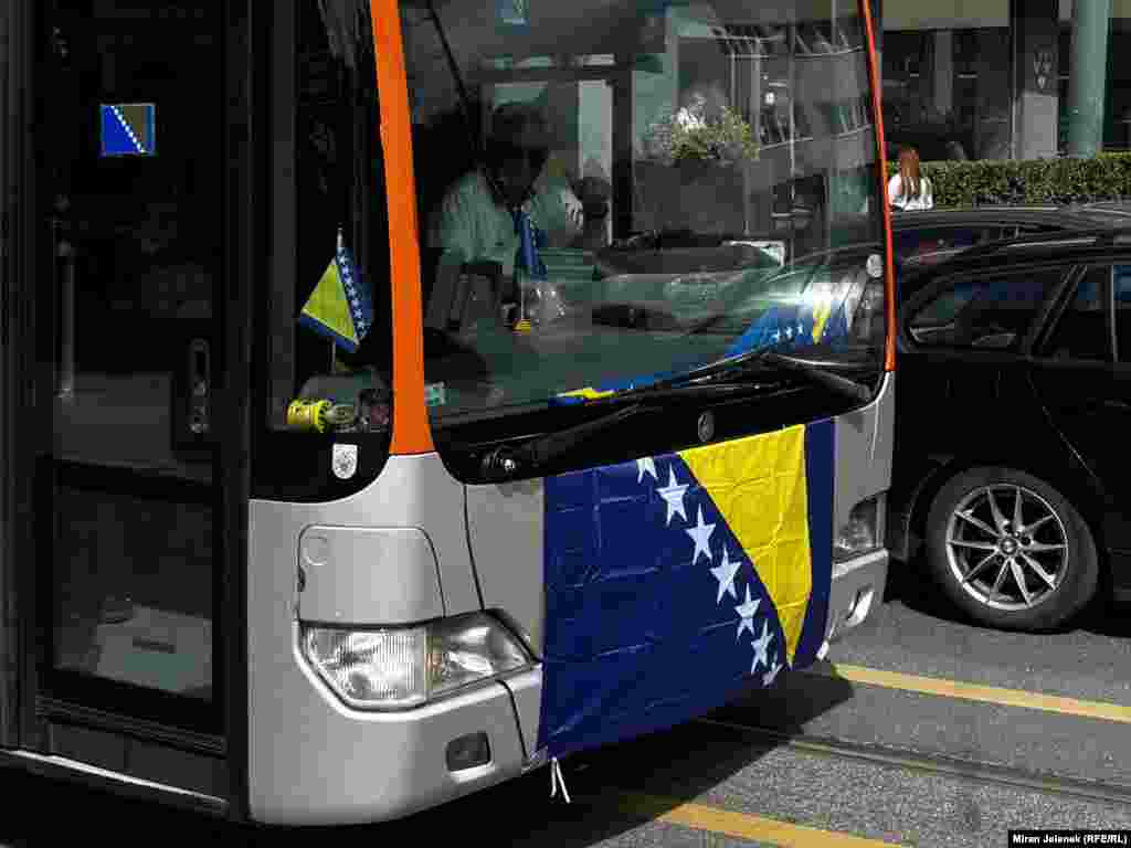 Autobus ukrašen zastavama prolazi gradskim središtem dok raste iščekivanje početka utakmice.