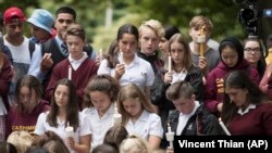 Students hold candles during a moment of silence on March 18 at a vigil to commemorate victims of the March 15 shooting in Christchurch.