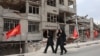 Iranian women walk past a residential building destroyed in a US-Israeli airstrike in Tehran.