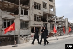 Iranian women walk past a residential building that was badly damaged in a US-Israeli air strike, in Tehran on April 13. .