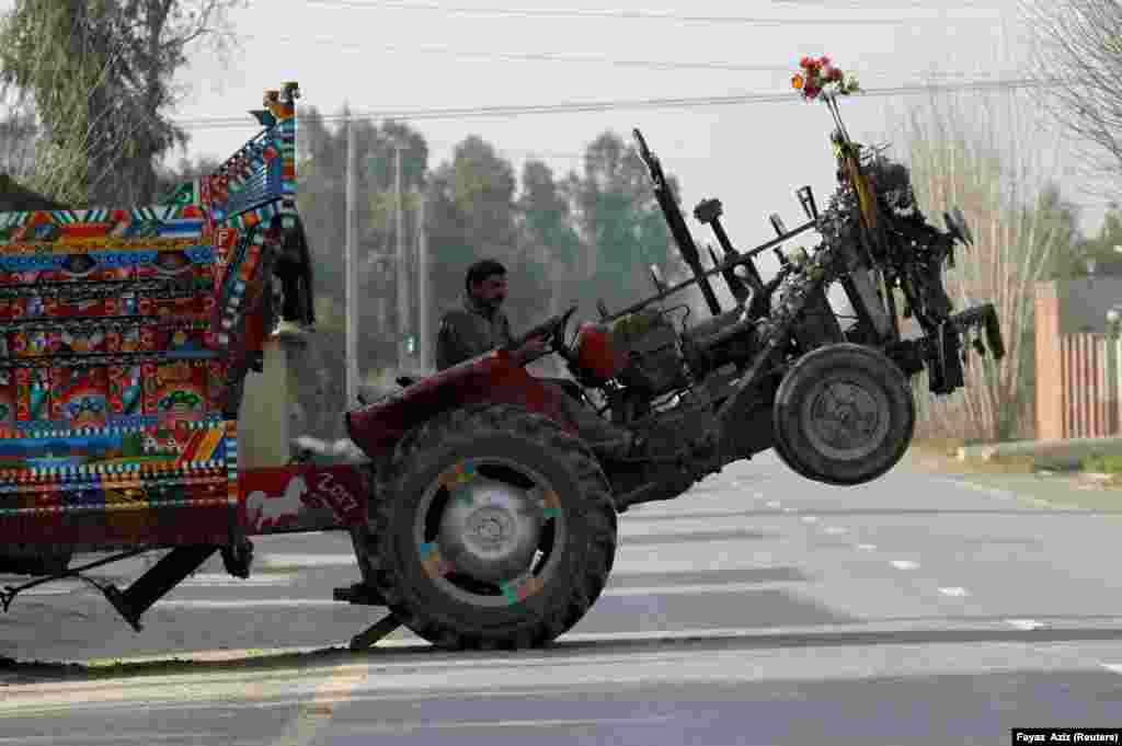 The front wheels of a tractor lift off the ground as the driver moves a heavy trailer outside Peshawar, Pakistan. (Reuters/Fayaz Aziz)