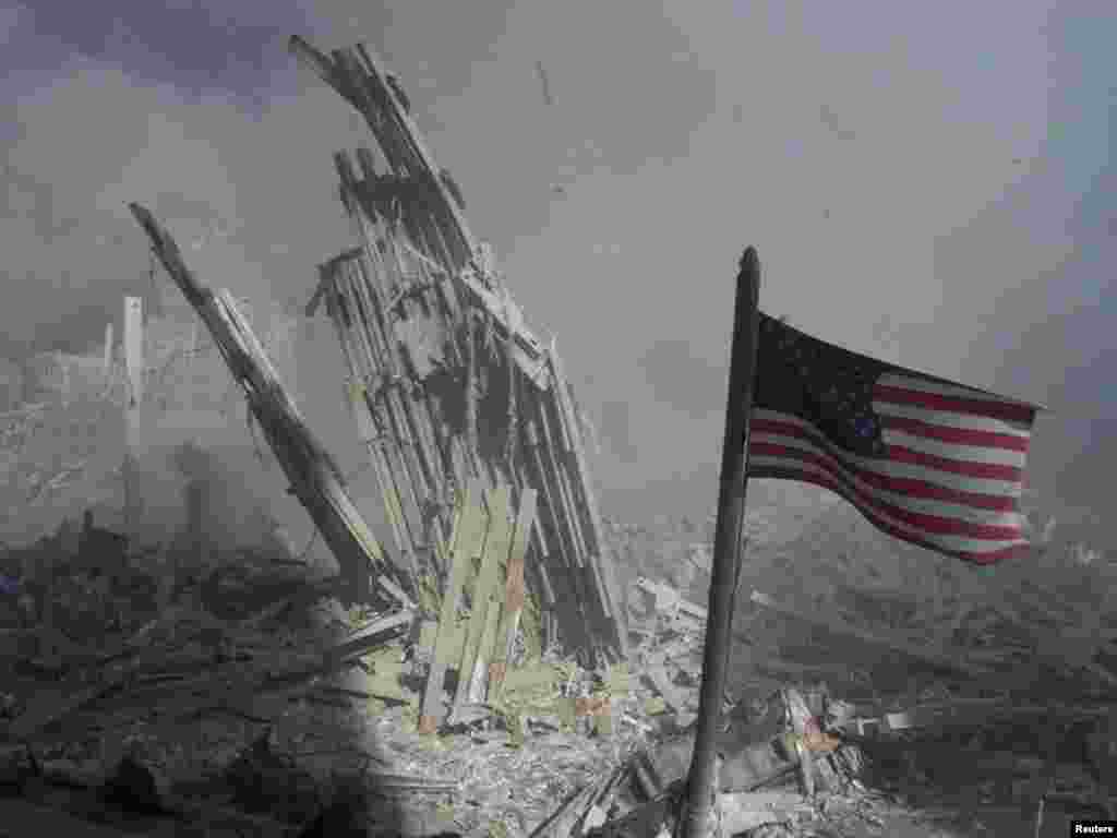 Am American flag flies near the base of the destroyed World Trade Center in New York, September 11, 2001. Planes crashed into each of the two towers, causing them to collapse. REUTERS/Peter Morgan 