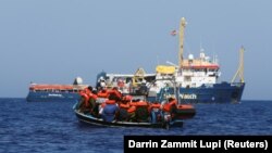 Izbeglice i migranti na jednom od drvenih čamaca kojim su napustili obale Libije, čekaju da ih spasi brod Sea Watch, avgust 2021. 