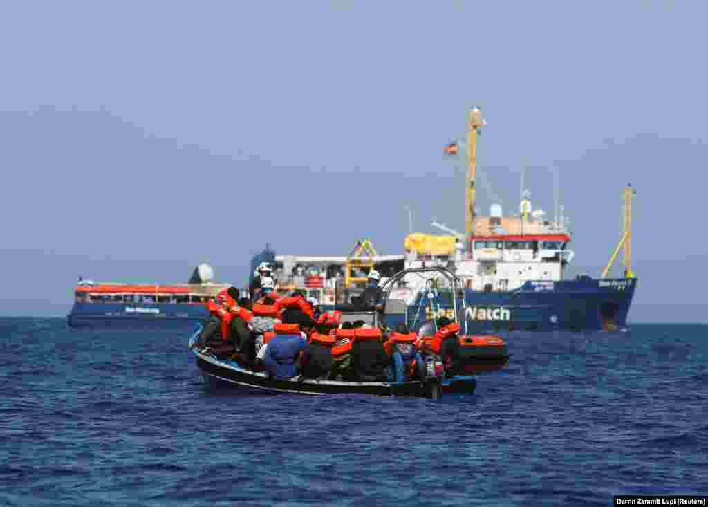 Mentőmellényeket oszt szét a menekültek között a Sea-Watch 3 legénysége, mielőtt átszállítanák az embereket a mentőhajóba