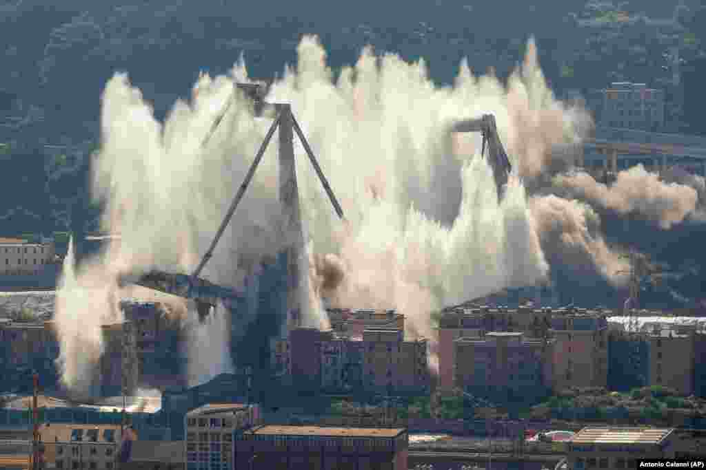 A cloud of dust rises as the remaining spans of the Morandi bridge are demolished in a planned explosion in Genoa, Italy, on June 28. (AP/Antonio Calanni)