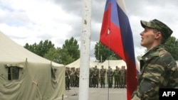 A Russian soldier raises the Russian flag at a border guard outpost in the South Ossetian village of Girei.