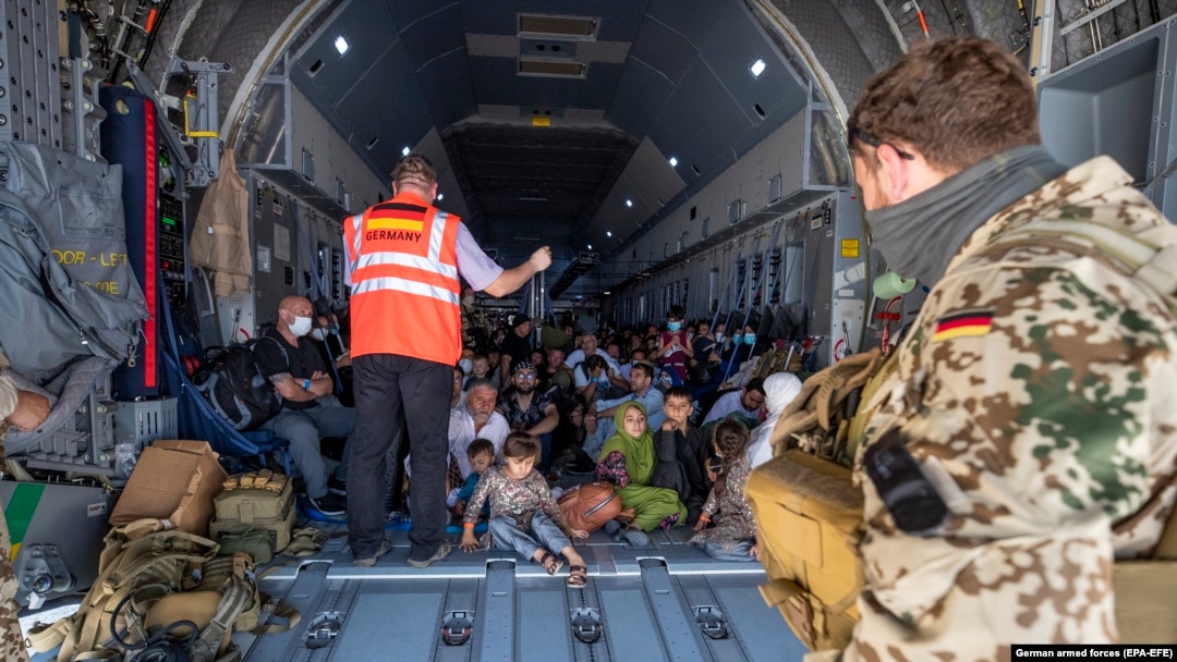 Un membru al staff-ului aeronavei informează evacuații din Afganistan, aflați la bordul unui avion de transport A400 al Forțelor Aeriene Germane, la sosirea pe aeroportul din Tașkent/Uzbekistan - 19 august 2021

