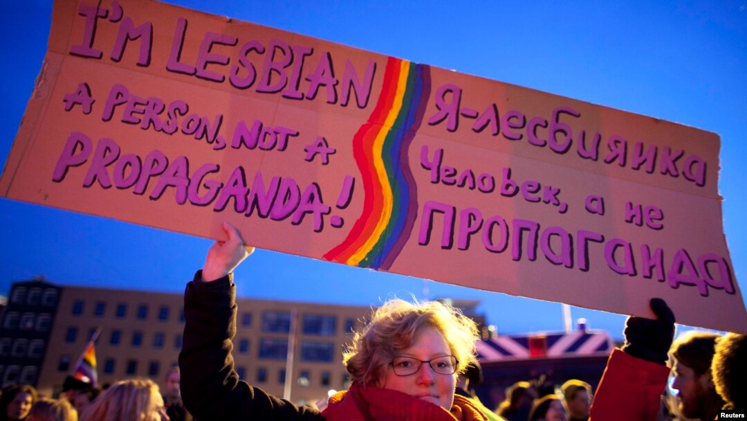 A woman holds up a banner during a demonstration by the gay community during a visit from Russian President Vladimir Putin to the Netherlands, in Amsterdam.