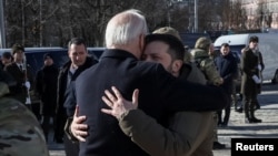 Președintele SUA, Joe Biden, și președintele Ucrainei, Volodimir Zelenski, se îmbrățișează după vizita la Zidul Amintirilor, unde au adus un omagiu soldaților ucraineni uciși în război. Kiev, Ucraina, 20 februarie 2023.