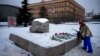  With Russia's Federal Security Service building in the background, a woman lays flowers to pay tribute to Aleksei Navalny at a monument in Moscow dedicated to gulag prisoners. 