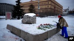  With Russia's Federal Security Service building in the background, a woman lays flowers to pay tribute to Aleksei Navalny at a monument in Moscow dedicated to gulag prisoners. 