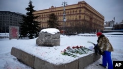 A woman lays flowers to pay tribute to Aleksei Navalny at the monument to political prisoners with the Federal Security Service building in the background in Moscow on February 21.