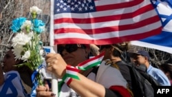 زنی ایرانی با پرچم‌های آمریکا و ایران در تجمع مخالفان جمهوری اسلامی در لس آنجلس