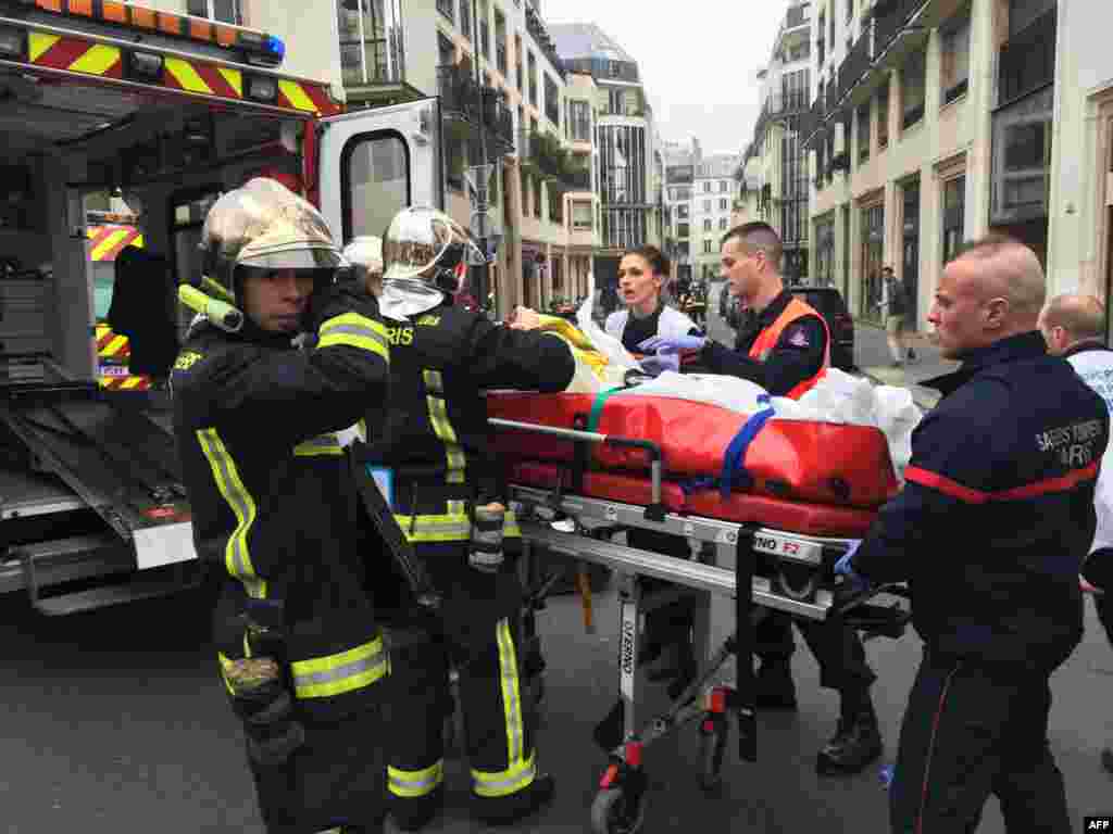 Firefighters carry an injured man on a stretcher in front of the Charlie Hebdo offices.