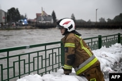 Пожарникарка стои до чували с пясък, натрупани срещу наводненията на река Бяла в Южна Полша, 14 септември 2024 г.