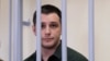 U.S. ex-Marine Trevor Reed, who was detained in 2019 and accused of assaulting police officers, stands inside a defendants' cage during a court hearing in Moscow in March 2020.