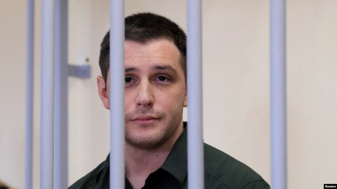 U.S. ex-Marine Trevor Reed, who was detained in 2019 and accused of assaulting police officers, stands inside a defendants' cage during a court hearing in Moscow in March 2020.