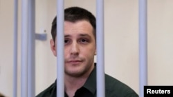 U.S. ex-Marine Trevor Reed, who was detained in 2019 and accused of assaulting police officers, stands inside a defendants' cage during a court hearing in Moscow in March 2020.