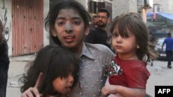 O fetiță palestiniană ține în brațe alți doi copii după o lovitură militară israeliană, în orașul Gaza, pe 12 octombrie 2023.