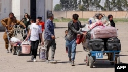 Afghan refugees carry their belongings after being deported from Iran at the Islam Qala border crossing between Afghanistan and Iran. (file photo)