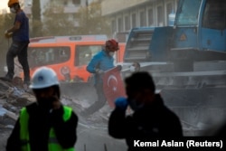 Жер сілкінісінен кейінгі құтқару жұмыстары кезінде Түркия туын әкетіп бара жатқан жұмысшы. Измир. 2 қараша 2020 жыл.
