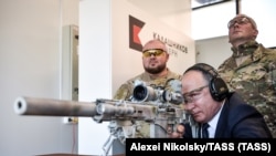 Vladgyimir Putyin orosz elnök egy fegyver távcsövébe néz a Kalasnyikov lőtéren egy katonai látogatóközpontban Moszkva környékén 2018. szeptember 19-én.